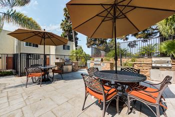 A patio with a table and chairs under umbrellas.